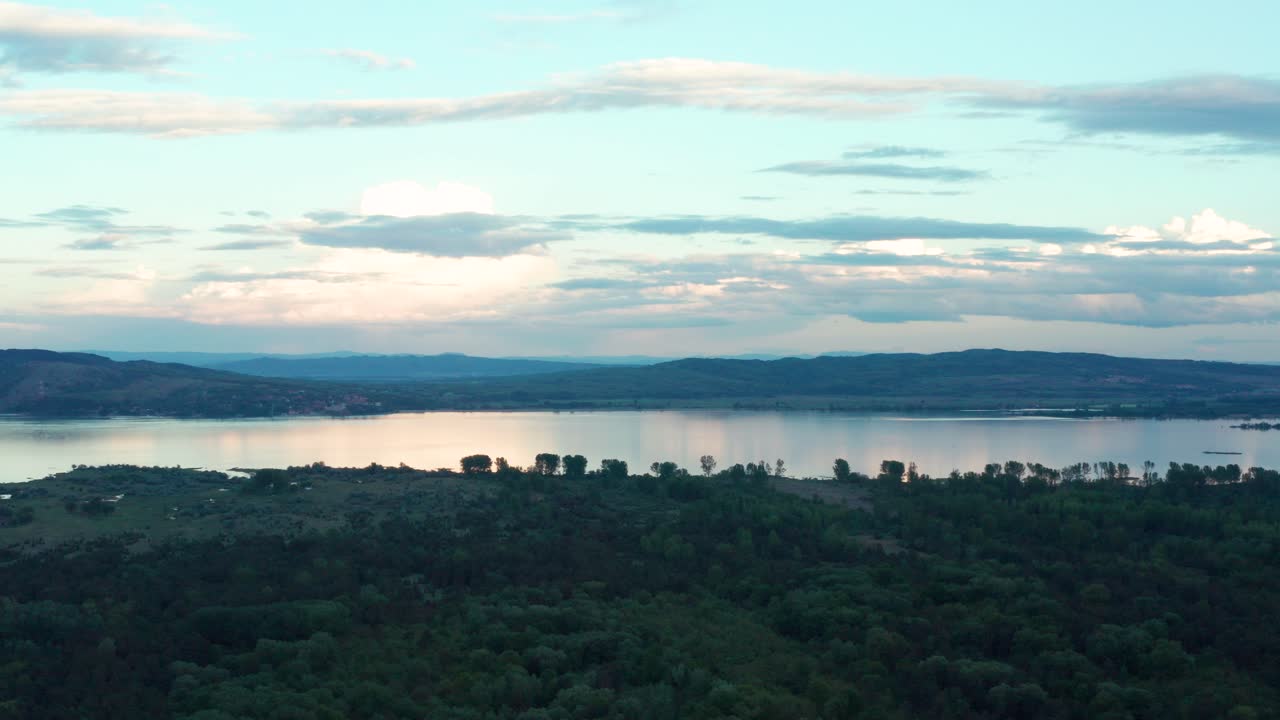 Aerial truck shot following along a placid lake in the morning.