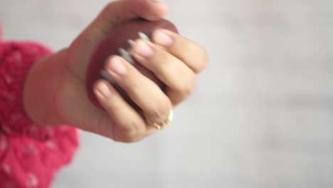 una mujer apretando una pelota de estrés marrón en forma de fútbol