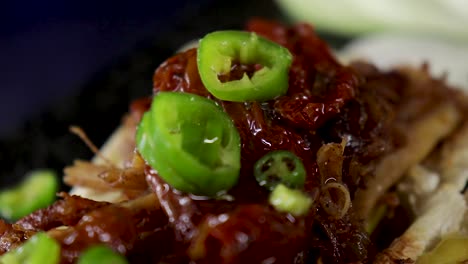 Extreme-close-up-of-green-sliced-chillies-being-topped-on-ripped-chicken-on-a-mini-ciabatta-loaf