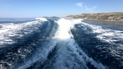 water crest behind a fast boat speeding over blue sea waters on a summer day