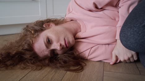 Zoom-in-video-of-depressed-young-caucasian-woman-lying-in-the-floor.