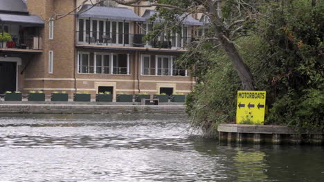 a yellow signboard showing the direction of travel for motorboats on the river thames in royal windsor