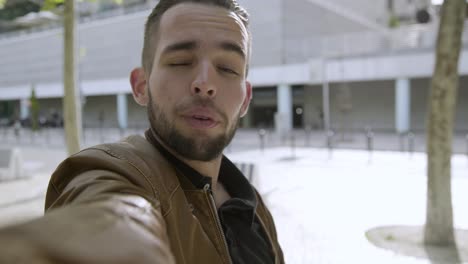 un joven guapo grabando un video en el parque.