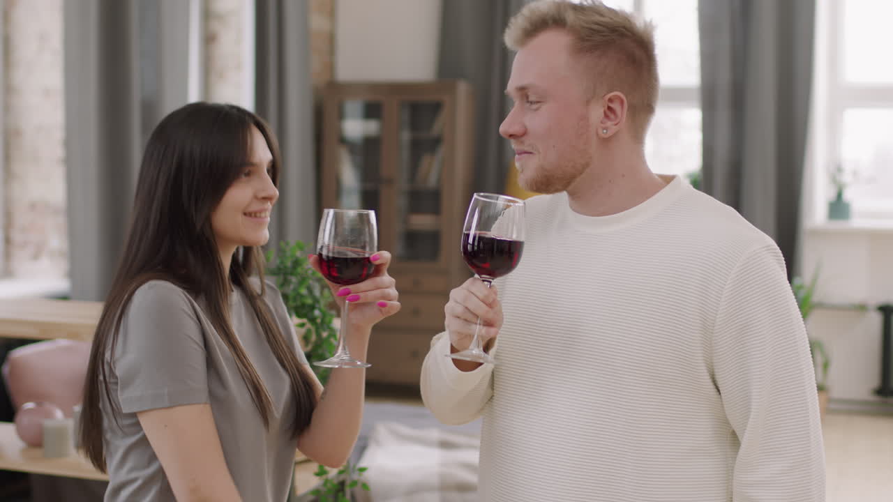 Young Woman and Man with Glasses of Red Wine Dancing
