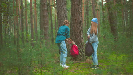 ladies in jeans reach down to retrieve their bags resting at the base of a tree in a serene forest, preparing to continue their hike, as they hang bags over their shoulders amid lush greenery