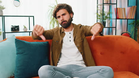 upset arabian man showing thumbs down, dislike bad work, disapproval dissatisfied feedback at home