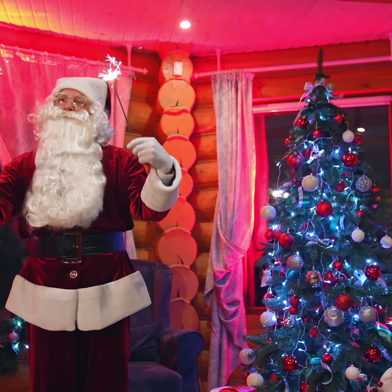 Happy Santa in cozy room at Christmas. Portrait of a cheerful Santa Claus with white beard holding Christmas lights and singing. Father frost near Christmas tree