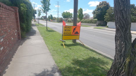 señal de trabajo en la carretera por delante en una calle suburbana