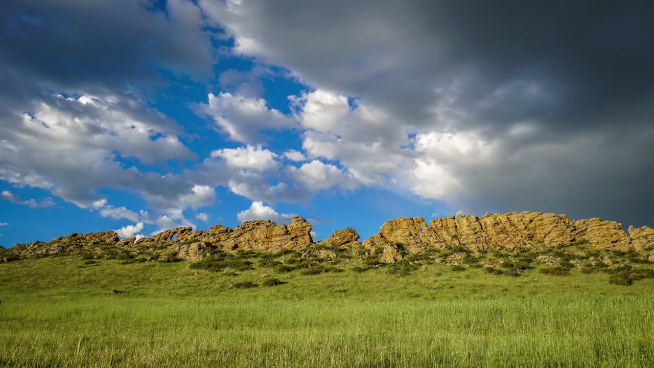 Time lapse of rolling clouds over a rock formation in Loveland, Colorado, Blue sky and green grass. Devils Backbone,