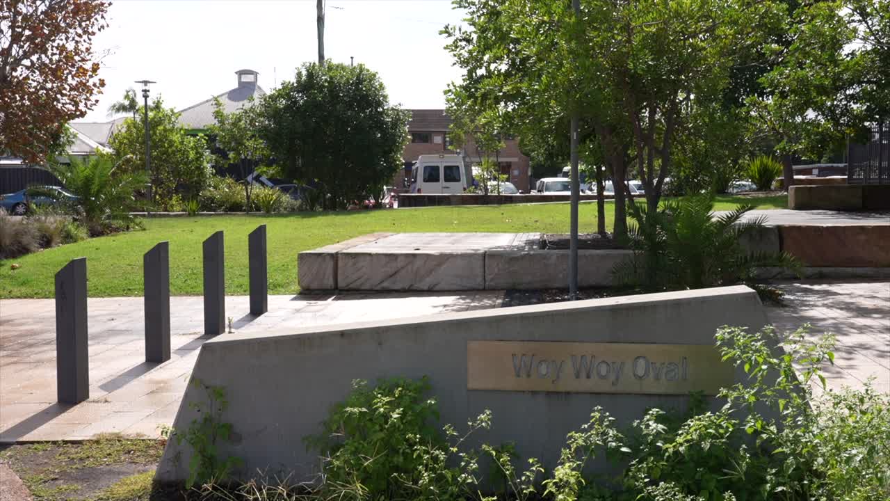 Placa da entrada do Woy Woy Oval com área de parque paisagístico e passarela, Woy Woy, Nova Gales do Sul, Austrália