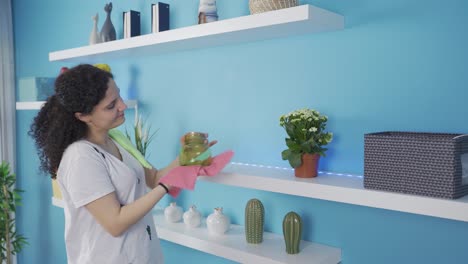 mujer joven limpiando el polvo de los artículos del hogar.