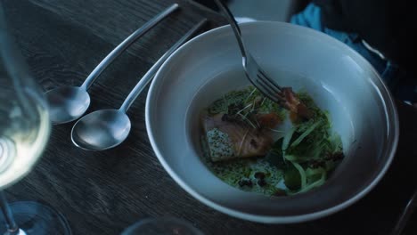 persona comiendo plato de pescado en un restaurante de comida fina, de cerca