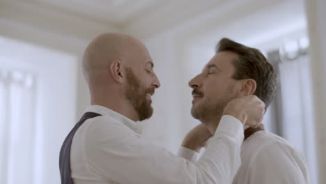 happy caucasian man tying his lover necktie for wedding ceremony