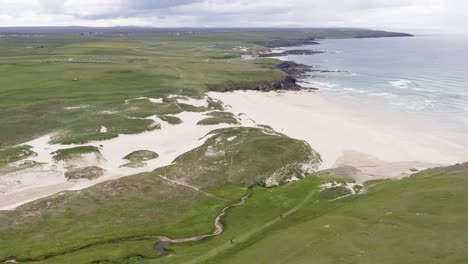 drone shot of eoropie beach in ness and the landscape beyond it on a sunny, summer's day