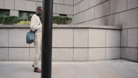 African-American-businessman-walking-through-city-using-smart-phone