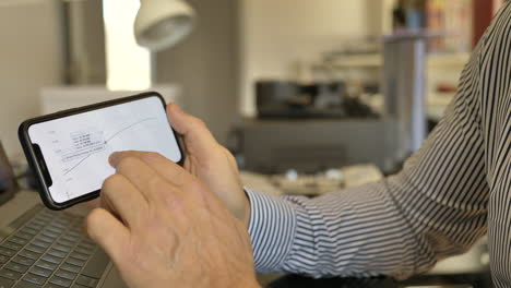 Closeup-shot-of-man-following-raising-profit-of-stock-market-on-smartphone-with-finger