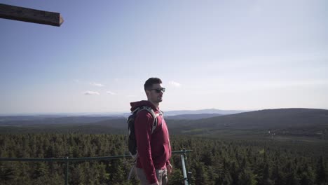 young tourist man in sun glasses at the top of hill, looking around and enjoying life