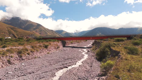 red bridge over dry riverbed in mountainous landscape