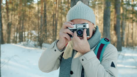 senior man taking pictures in a snowy forest