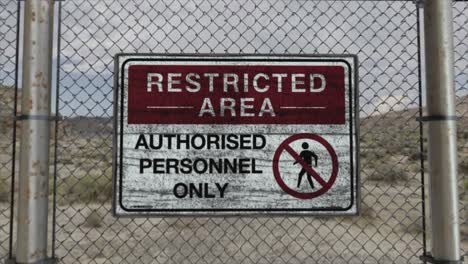 high quality 3d cgi render with a smooth dollying-in shot of a chainlink fence at a high security installation in a desert scene, with a restricted area - authorised personnel only sign