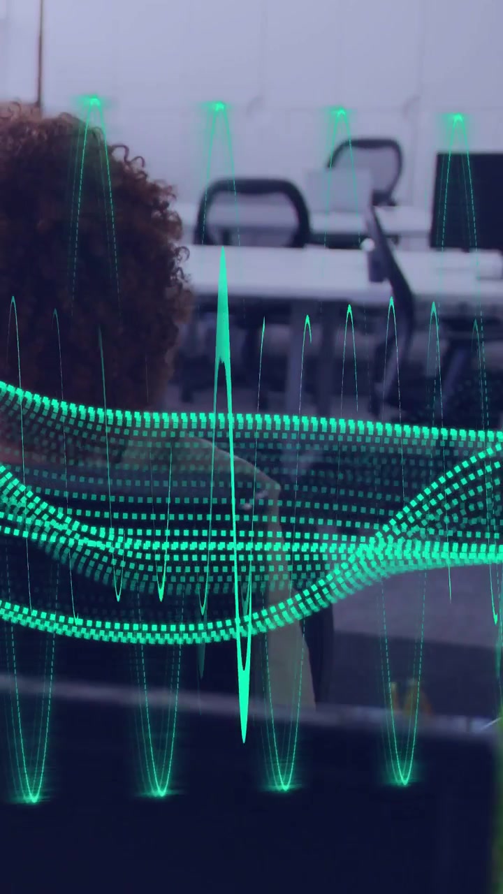 Vertical video: Camera panning, woman sitting desk, teal wave pulsing over desks showing tech demo