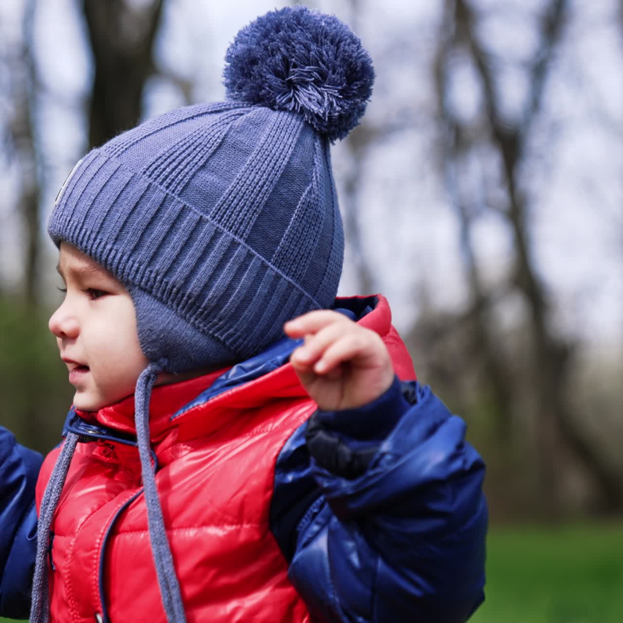 Cute baby boy is unhappy and wailing along his way. Little kid on the walk in spring