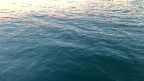 calm sea without waves, dark water gently swings on the horizon, a small reflection of the sun in the upper left-hand side