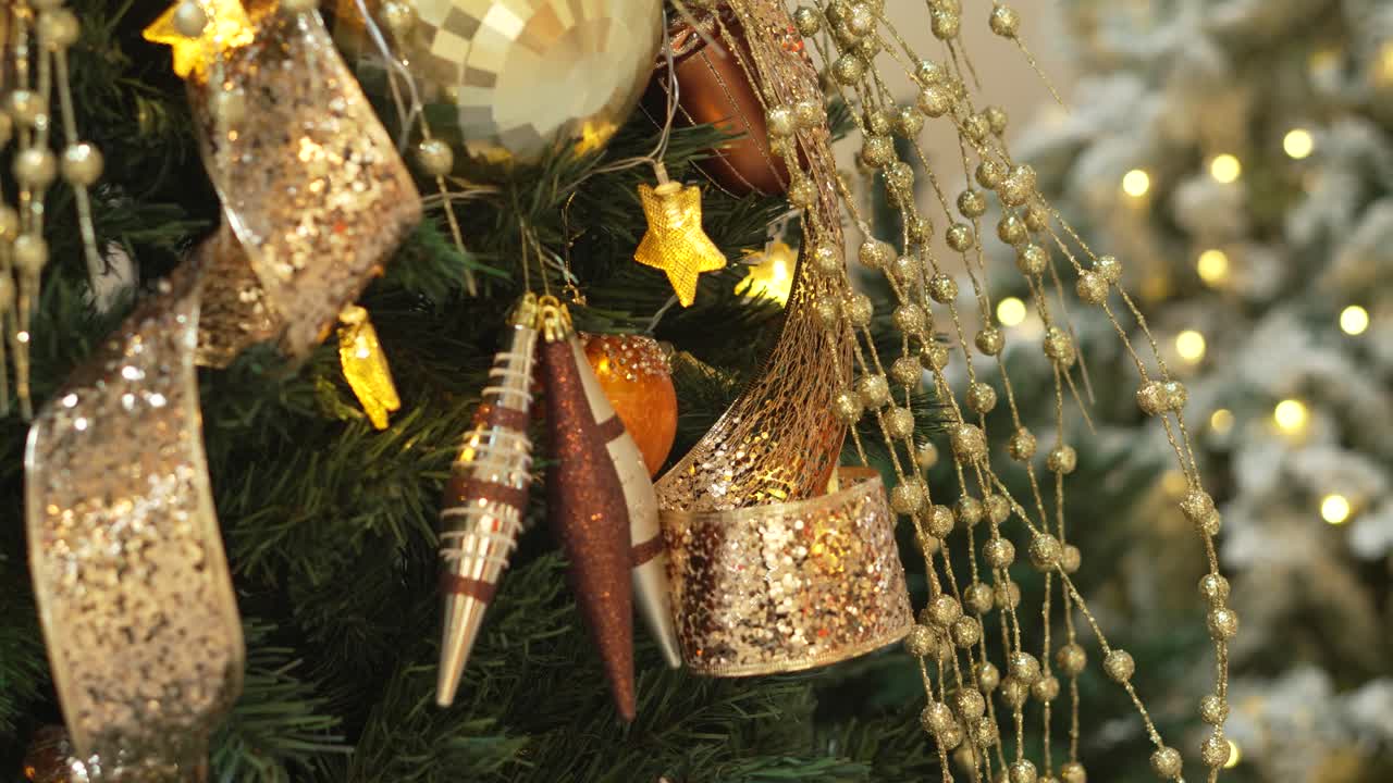 close-up decorated Christmas tree ornaments, featuring glittery gold ribbons, shiny baubles, and twinkling star-shaped lights.
