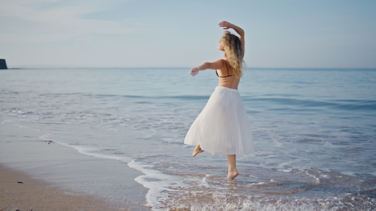 여름 아침 바다 파도에서 현대적인 안무 연습을 하는 공연자.