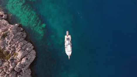 barco a la deriva en agua de mar azul en phaselis, antigua licia - antalya, turquía - vista aérea de arriba hacia abajo