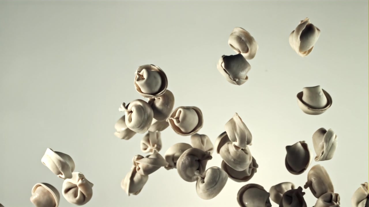 Raw Dumplings Falling in Slow Motion Against a White Background