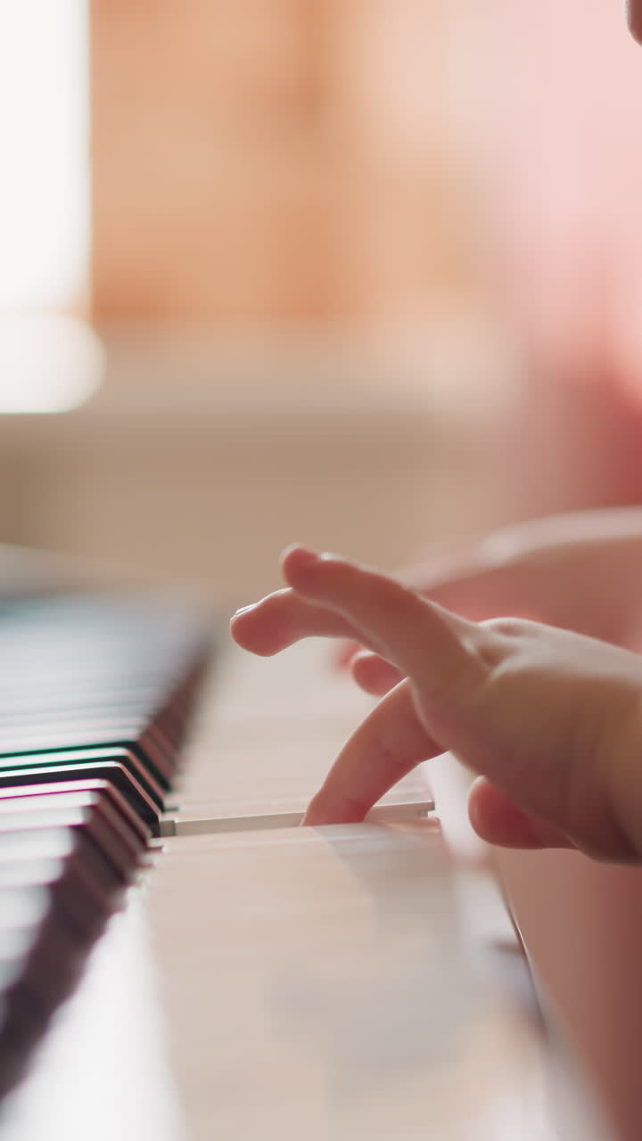 Cute boy in white shirt plays synthesizer on apartment blurry background closeup. Little kid learns musical composition at home lesson in children room