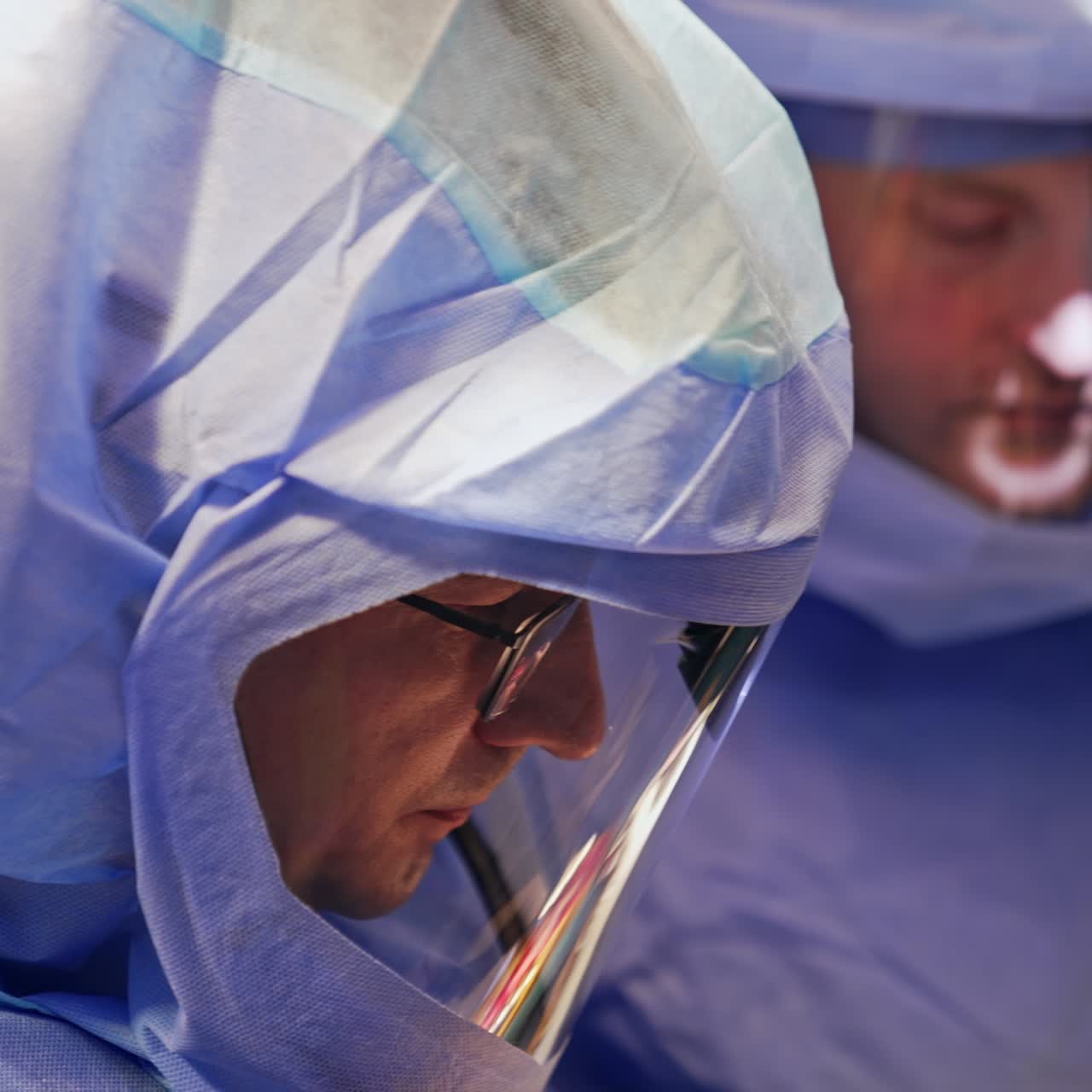 Adult surgeons wear special protective suits at operation. Focused doctors with flashlights on their heads close up portraits