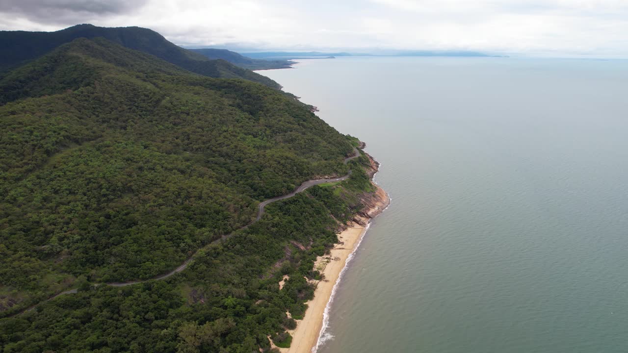 Aerial View of Coastal Road Winding Through Lush Mountains Beside the Ocean