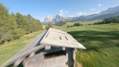 fpv racing drone flying over green valley with dolomites mountains in background