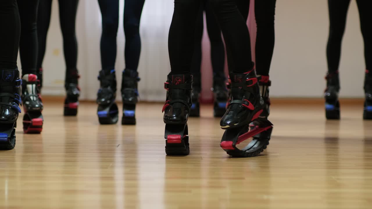 Ragazze sportive si preparano per un allenamento con gli stivali Kangoo Jumps in una grande palestra.