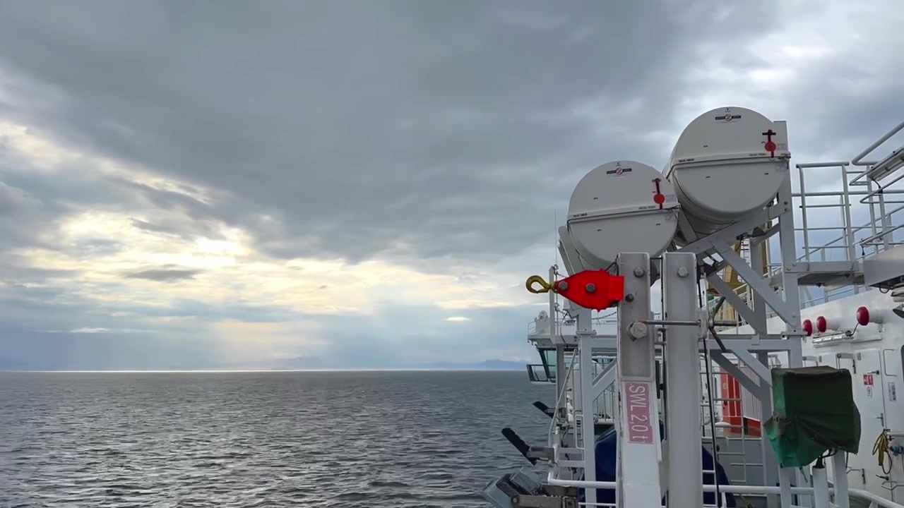 Ferry crossing the North Sea towards the Outer Hebrides, Scotland. Dramatic cloud formations hang above distant island mountains while deep blue waters stretch across the horizon, capturing the