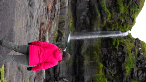 Mujer-Admirando-La-Hermosa-Naturaleza-Feroesa-Junto-A-La-Cascada-De-Mikladalur,-Kalsoy