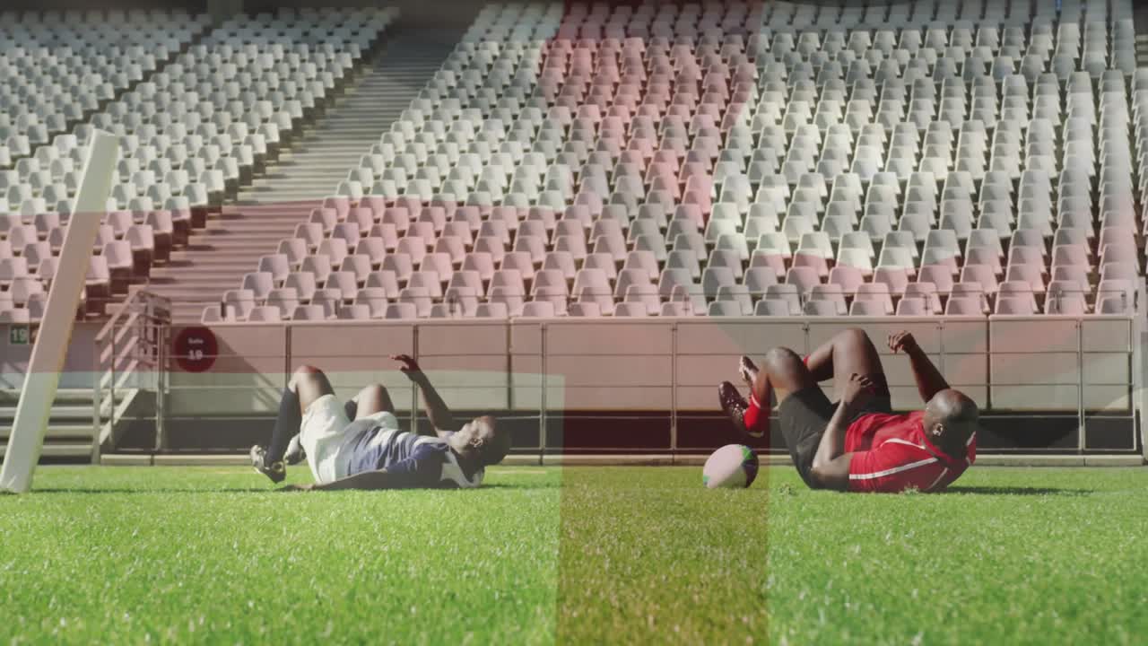 Rugby-spiller i rødt spurter mot mål for å score en try, gråblå forsvarer kaster seg for å takle mens han holder ballen
