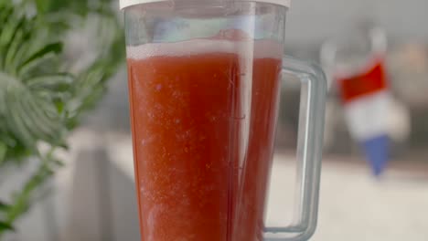 Delicious-juicy-red-fruit-smoothie-spinning-slow-motion-in-blender-in-front-of-French-flag-shallow-focus