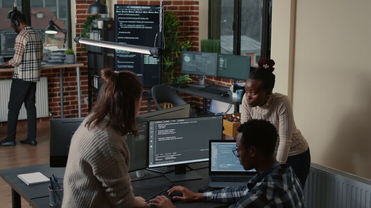 Programmeur zit aan een bureau te discussiëren met een gemengd team van softwareontwikkelaars over kunstmatige intelligentie