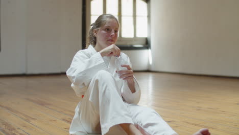 static shot of tired karateka drinking water in gym