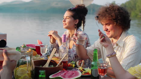 positive woman chatting with friends at lake party