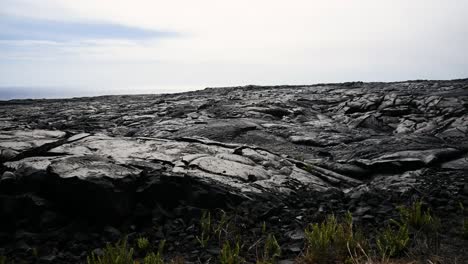 driving by fresh lava flows reflecting the light and the thin cloud in the background as well as the pacific ocean