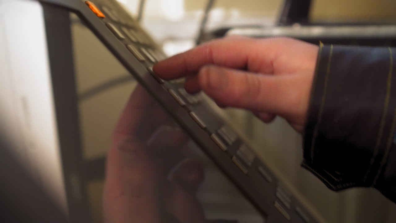 el trabajador presiona con la mano las teclas eligiendo el programa en el panel de control