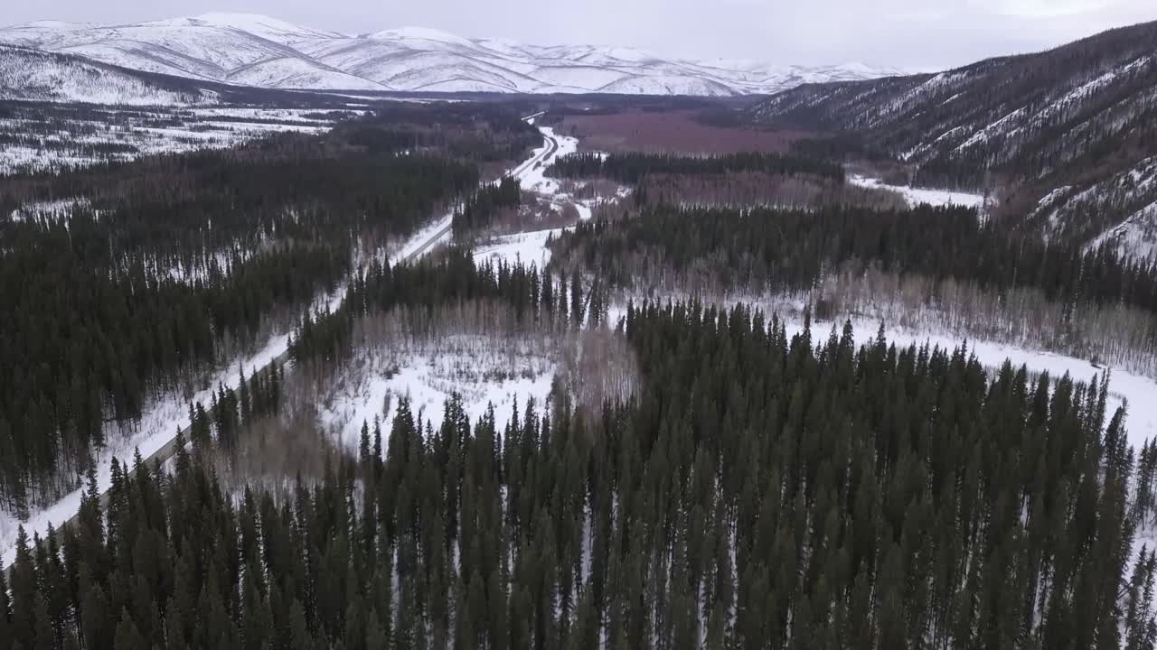 vista aérea inclinada hacia arriba sobre el desierto de alaska, colinas cubiertas de nieve en el fondo, río congelado y estanque