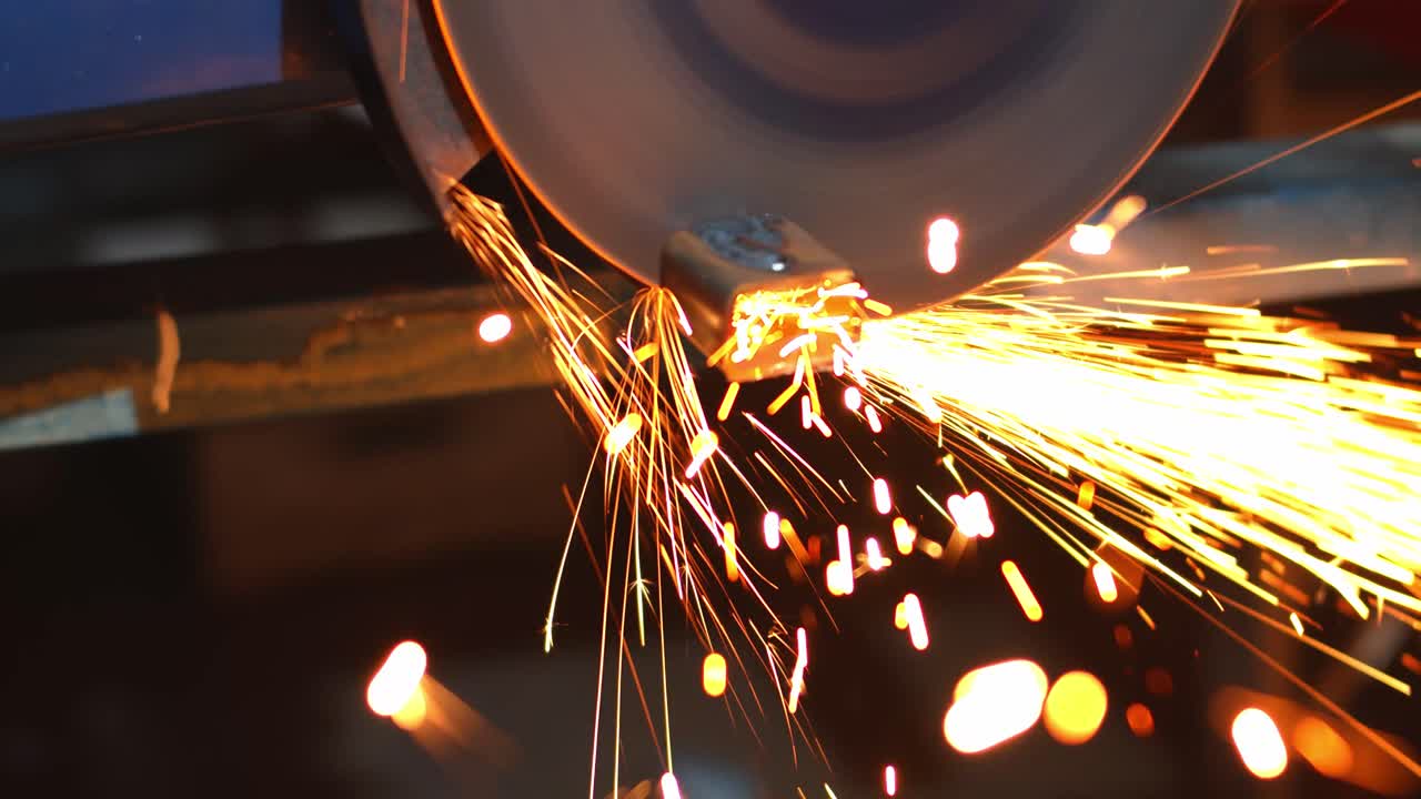 Angle grinder with massive disk cutting through metal with many sparks, handheld view