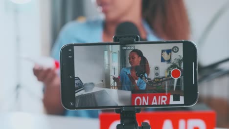 young african american woman beauty blogger sits near phone with camera on