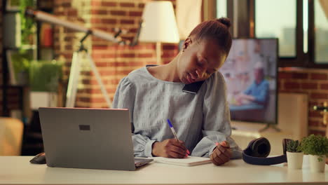 freelancer escribiendo notas de una llamada telefónica