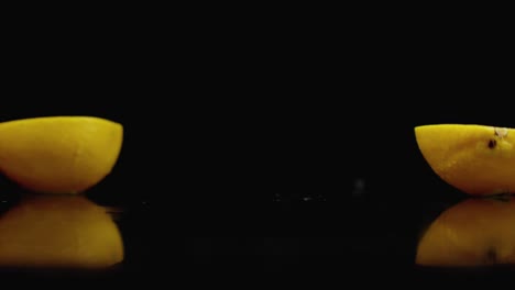 cut yellow lemon fall into 2 parts glass with water splashes in slow motion on a dark background.